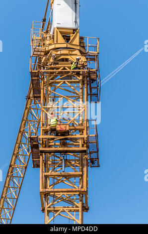 Arbeitnehmer Wartung Bau kran auf klaren Himmel und Fliegen Flugzeug mit einer Kondensation Streifen in einem Hintergrund in Kattowitz, dem Schlesischen Hochland, Polen. Stockfoto