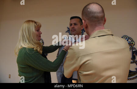 170203-N-RX 668-208 NEWPORT, R.I. (Feb. 3, 2017) Air Force Senior Master Sgt. Joseph Herrera, ein Faculty Advisor zu den älteren Soldaten Akademie (Meer) in Newport, Rhode Island ist als Honorary Chief Petty Officer (Hcpo) von seiner Frau Jenna Herrera, und der Master Chief Petty Officer der Marine (MCPON) Steven Giordano festgesteckt. Nur genehmigt von der MCPON, hcpo Anerkennung soll superior Auseinandersetzung mit der kollektiven U.S. Navy Chief Petty Officer Gemeinschaft nachhaltig zu erkennen und Soldaten. (U.S. Marine Foto von Mass Communication Specialist 2. Klasse Jess Lewis/freigegeben) Stockfoto