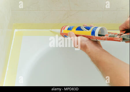 Arbeitnehmer setzt Silikondichtmittel die Verbindung zwischen Wanne und Wand abdichten. Stockfoto