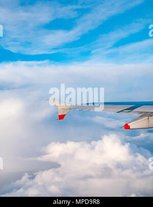 British Airways Airbus 319 Flugzeug Flügel aus dem Flugzeug Fenster beim Flug über Puffy und wispy Wolken und dem klaren, blauen Himmel in Großbritannien gesehen Stockfoto