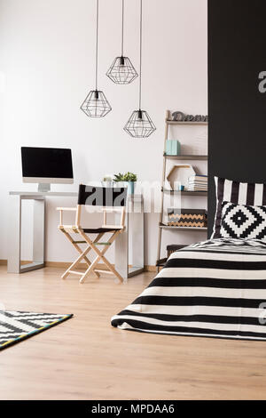 Schwarz und Weiß Home Interior mit Bett, Pendelleuchte, Schreibtisch, Stuhl und Computer Stockfoto