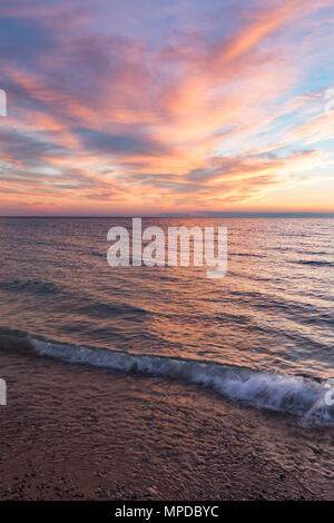 Lebendige Farben reflektieren aus Wolkenformationen, wie die Sonne über den Lake Michigan zu einem leeland Michigan Strand setzt Stockfoto