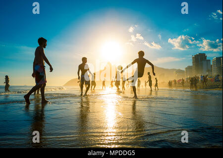 RIO DE JANEIRO - 23. FEBRUAR 2014: Silhouetten der Brasilianer spielen Keepy Uppy altinho Beach Soccer auf dem Sunset Ufer am Posto Nove Ipanema Beach Stockfoto