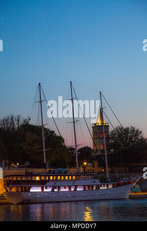 Boote und Yachten im Hafen an der Adria Hafen von Zadar Kroatien bei Dämmerung gesehen mit einer untergehenden Sonne und beleuchteten Gebäuden und Hafen Stockfoto