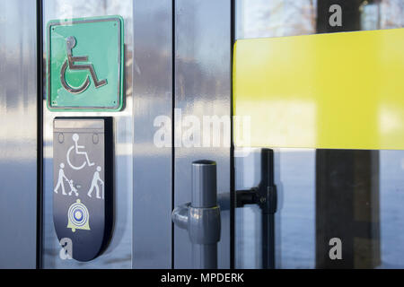 Anruf auf Vordertür aus Glas, die für den Aufbau und die Plakette mit dem Bild von behinderten Menschen im Rollstuhl und Menschen mit Stock Stockfoto