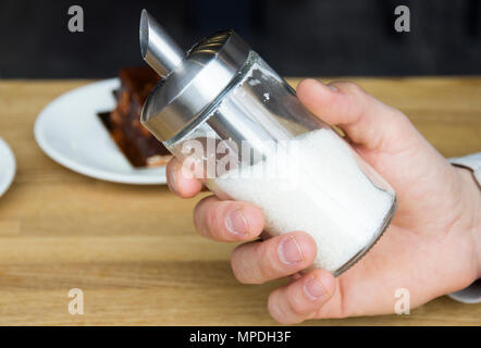 Glas Spender mit Zucker in der Hand des Menschen Stockfoto