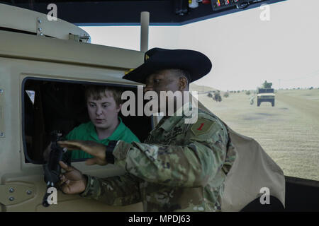 Sgt. Sampson Ifegwu, die Kavallerie Scout mit der 5. Staffel zugeordnet, 4.Kavallerie Regiments, 2. gepanzerte Brigade Combat Team, 1.Infanterie Division, zeigt Alex Jost, eine Landwirtschaft/Industrial arts Lehrer von Chapman High School, wie ein M4 Carbine Waffe während der High School zukünftige Landwirte von Amerika Besuch am Close Combat Tactical Trainer Center in Fort Riley verwenden 27. Zusammen mit diesem Simulator Übung hatten die Studenten auch die Möglichkeit eine simulierte UH 60 A/L/M Black Hawk Helikopter Pilot. (Sgt. Takita Lawery, 19 Public Affairs Abteilung) Stockfoto