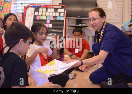 Petty Officer 1st Class Tiffany Lux, ein boatswains Mate stationiert an Bord der U.S. Coast Guard Cutter Morgenthau (WHEC722), zusammen mit Studenten aus Kalihi Waene Volksschule in Honolulu, 3. März 2017 liest. Lesung über Amerika Tag ist eine bundesweite Lesung fest, das jährlich auf Dr. Seuss' Geburtstag, März 2. Das Lesen über Amerika-Programm, das von der National Education Association ist ein ganzjähriges Programm zu motivieren Kinder und Jugendliche durch Veranstaltungen, Partnerschaften und Ressourcen zu lesen. (U.S. Coast Guard Foto von Petty Officer 3. Klasse Amanda Levasseur) Stockfoto