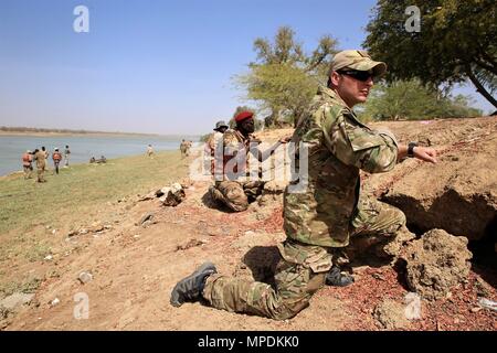 Ein U.S. Army Special Operations Soldat zusammen mit Soldaten aus der tschadischen Armee ziehen Sicherheit während der Ausbildung von Seeleuten auf dem Fluss Chari in N'Djamena, Tschad März 3, 2017 als Teil der Musketen 17. Die tschadische Soldaten wurden simuliert Waffen als Dies ist die erste Phase der Strand infiltration Training. Flintlock ist eine jährliche Übung spezielle Operationen, an denen mehr als 20 nation Kräfte, stärkt Sicherheit Institutionen, fördert den internationalen Austausch von Informationen, und entwickelt die Interoperabilität zwischen den Partnerländern Nation in Nord- und Westafrika. (Armee Foto von Sgt. Derek Hamilton) Stockfoto