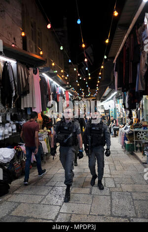 Mitglieder der israelischen Sicherheitskräfte, die in der Al Wad oder Haggai Street im muslimischen Viertel spazieren gehen, das während des heiligen muslimischen Monats Ramadan in der Altstadt von Jerusalem mit festlichen Lichtern dekoriert ist. Moslems auf der ganzen Welt beobachten einen Monat des Fastens, um der ersten Offenbarung des Korans gegenüber Mohammed nach islamischem Glauben zu gedenken. Stockfoto