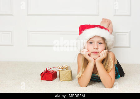 Mädchen in einem Weihnachten Cap liegt außerhalb der verpackten Geschenke Stockfoto