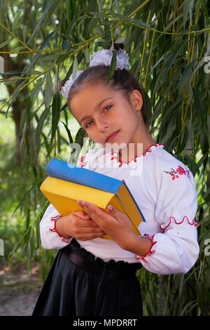 Schönes kleines Mädchen 7 Jahre in Stickerei Bücher in Farbe ukrainische Flagge Stockfoto