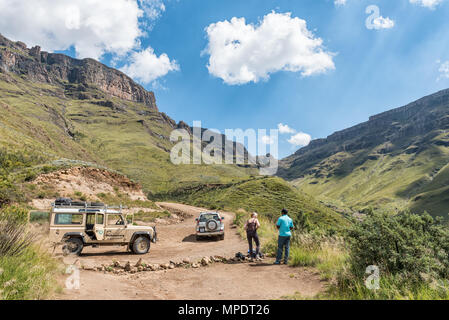 HIMEVILLE, SÜDAFRIKA - 24. MÄRZ 2018: Zwei nicht identifizierte Touristen und Fahrzeuge mit Allradantrieb auf der Sani Pass. Die serpentinen der Sani Pass Stockfoto