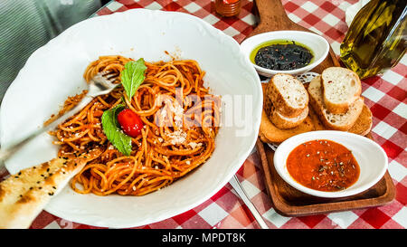 Napolitan oder bolognese Spaghetti mit Tomaten und Oliven paste serviert. italienisches Essen Konzept. Stockfoto