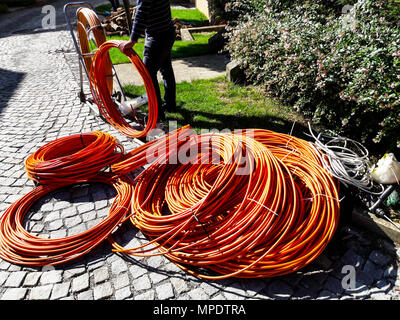 Orange Faser- oder Glasfaserkabel an Garten für die Ausgrabung. Bau für Internet Stockfoto