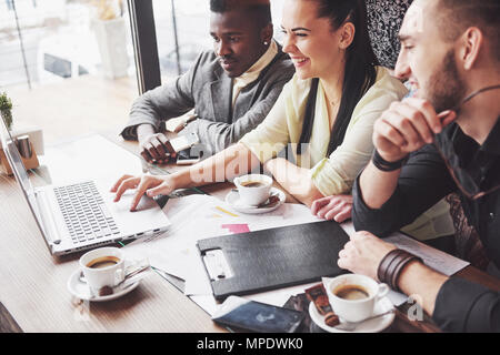 Multi-ethnische Geschäftsleute, Unternehmer, Business, Small Business Konzept, Frau, Kollegen etwas auf Laptop, wie sie um einen Konferenztisch sammeln Stockfoto