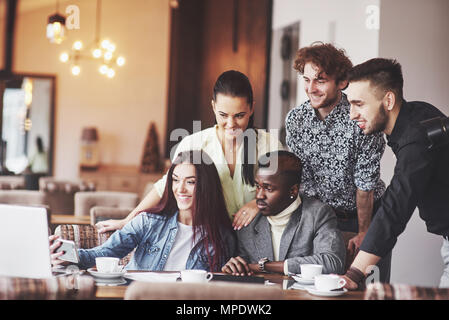 Multi-ethnische Geschäftsleute, Unternehmer, Business, Small Business Konzept, Frau, Kollegen etwas auf Laptop, wie sie um einen Konferenztisch sammeln Stockfoto