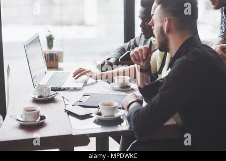 Multi-ethnische Geschäftsleute, Unternehmer, Business, Small Business Konzept, Frau, Kollegen etwas auf Laptop, wie sie um einen Konferenztisch sammeln Stockfoto