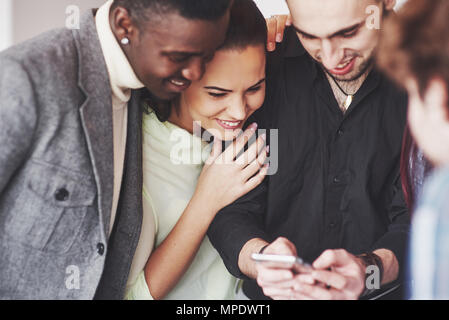 Portrait von fröhlichen jungen Freunden bei smart phone, während im Cafe sitzen. Gemischte Rasse Menschen in Restaurant mit Handy