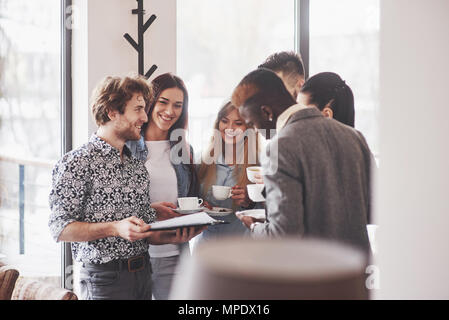 Erfolgreiche Geschäftsleute sind die Verwendung von Minianwendungen, reden und lächeln, während der Kaffeepause im Büro Stockfoto