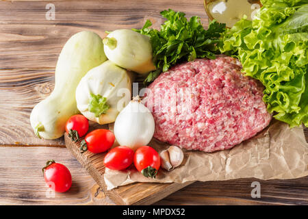 Mixe von Hackfleisch Hackfleisch/Faschiertes Rind- und Schweinefleisch festgelegt für das Kochen Grill Steaks kebabs Würstchen gebraten auf Feuer essen Gemüse Tomaten Blätter Kopfsalat Stockfoto