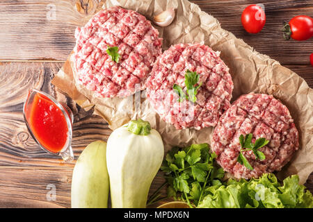 Mixe von Fleisch schnitzel Hackfleisch/Faschiertes Rind- und Schweinefleisch festgelegt für das Kochen Grill Steaks kebabs Würstchen gebraten auf Feuer essen Gemüse Tomaten Blätter Stockfoto