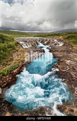 Malerischer Blick auf einen Wasserfall mit blaue Färbung, im Hintergrund ein Gebirge - Ort: Island, Golden Circle Stockfoto