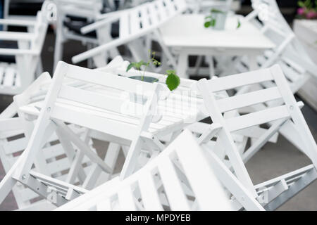 Viele der invertierten weiße Plastikstühle auf Tabellen in geschlossen Restaurant auf der Terrasse. Schöne Grafik Chaos, interessanten Hintergrund Stockfoto