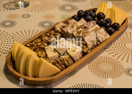 Käseplatte: Emmental, Camembert, Blauschimmelkäse, Cheddar, Traube, Walnüsse auf wooen Oberfläche Stockfoto