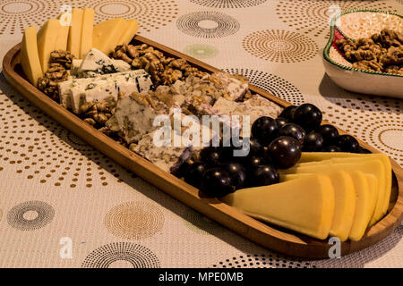 Käseplatte: Emmental, Camembert, Blauschimmelkäse, Cheddar, Traube, Walnüsse auf wooen Oberfläche Stockfoto