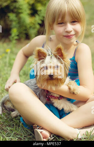 Mädchen 6 Jahre alt auf dem Gras Holding ein Yorkshire Terrier Stockfoto