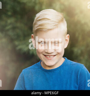 Blonde Teenager im blauen T-Shirt lächelnd. Herzlich Lachen, ein lebendiges Gefühl. Ehrliche Junge. Stockfoto