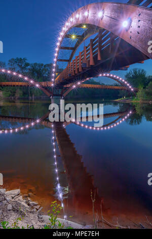 Die tridge bei Nacht, überspannt den Zusammenfluss von Chippewa und Tittabawassee Flüsse in Chippewassee Park in Midland, Michigan. Die Brücke reflektiert in t Stockfoto