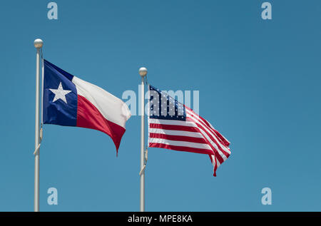 Der Staat Flagge von Texas und Amerikanische Flagge im Wind am Fahnenmast. Blauer Himmel mit kopieren. Stockfoto