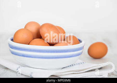 Käfig frei, braune Eier in eine weisse und eine blaue Schale am Küchentisch. Weißer Hintergrund mit kopieren. Stockfoto