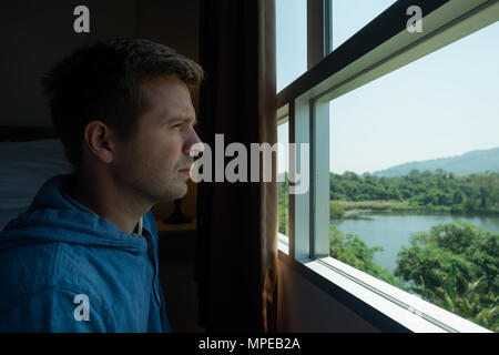 Seitenansicht eines Mannes Sehnsucht und schauen durch das Fenster. Stockfoto