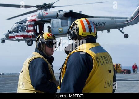 170214-N-ZQ 712-0100 PAZIFISCHEN OZEAN (Feb. 14, 2017) Aviation Bootsmann der Gehilfen 2. Klasse Brandon Latimer, Links, und Andrew Roseberry, sowohl für die amphibische Landung Schiff USS America zugeordnet (LHA 6), bereiten Sie den Flight Deck als MH-60 Sea Hawk zum 'Platzhalter' der Hubschrauber Meer Combat Squadron (HSC) 23 zugeordnet Verordnung zum Flight Deck bietet während einer Munition auf - Laden. (U.S. Marine Foto von Mass Communication Specialist Seaman Apprentice Tschad Swysgood/Freigegeben) Stockfoto