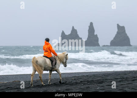 Felssäulen am Meer in Vík í Mýrda, einem abgelegenen Dorf am Meer. Meeresstapel, genannt Reynisdrangar, erheben sich majestätisch aus dem Atlantik. Dyrhólaey eine 120 Meter hohe Landzunge, die sich bis ins Meer erstreckt und einen beeindruckenden Naturbogen bildet, der sich im westlichen Teil des Stadtteils Mýrdalur befindet. Island. Stockfoto