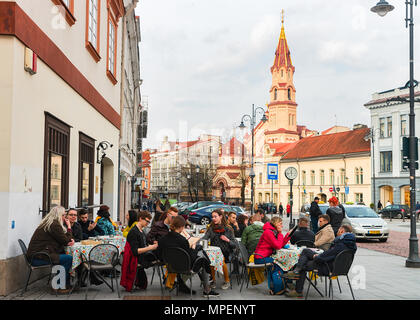 Vilnius, Litauen - 1. April 2017: Touristen in open air Street Cafe in der Altstadt von Vilnius, in Litauen. Kirche St. Nikolaus auf Th Stockfoto