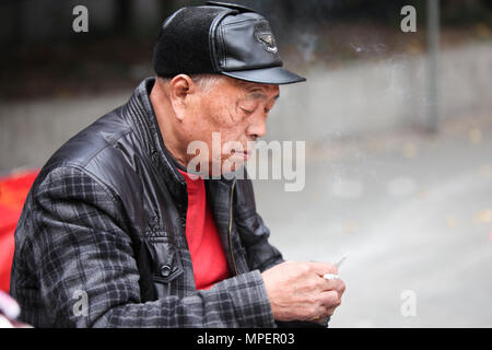 Chinesische alte Mann rauchen und Glücksspiel mit einem Karten Spiel in Hangzhou, China Stockfoto