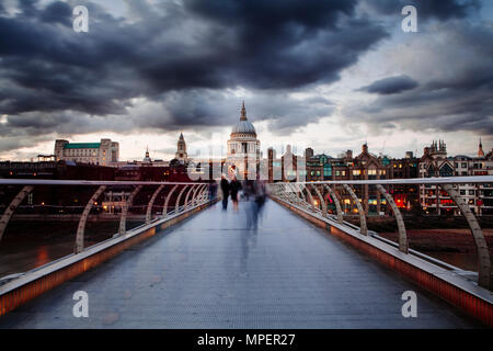 Am frühen Abend auf der Londoner Millennium Bridge mit Menschen Kreuzung in motion blur und ein Blick auf die St. Pauls Cathedral. Stockfoto
