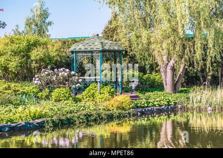 Fragment einer schönen Ort am See in der Mezhyrrya Park in der Nähe von Kiew zu entspannen. Vor dem Hintergrund der blühenden Bäume, Büsche und rhododendree Stockfoto
