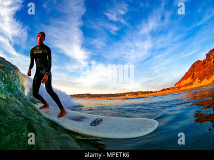 Latino surfer Juan Gonzalez Surfen bei Sonnenuntergang in Torrey Pines State Beach, San Diego, CA. Stockfoto