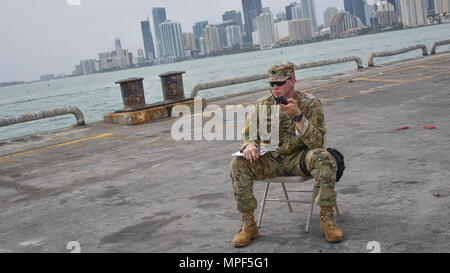 Us-Armee finden Sgt. Ryan A. Garvey, einem chemischen, biologischen, radiologischen und nuklearen Fachmann mit der 329 Unternehmen der chemischen Industrie in Orlando, Fla., wartet auf Rückmeldung von seiner Mannschaft, die Entnahme von Proben bei einer gemeinsamen Gefahr material Übung mit der US-Armee und die miami-dade Feuerwehr Abteilung am Hafen von Miami, Feb 18, 2017 waren. Die 329. der chemischen, biologischen, radiologischen und nuklearen (CBRN) Unternehmen (Aufklärung und Überwachung) von Orlando, Fla., 469Th der Armee finden im Krankenwagen, von Wichita, Kan., und der Unterstützung der Florida National Guard Stockfoto