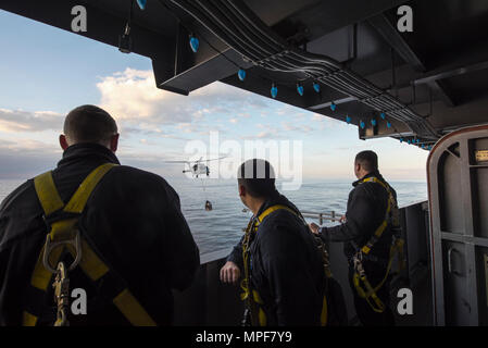 170218-N-WG 055-006 MITTELMEER (Feb. 18, 2017) Segler ein MH-60S Sea Hawk von Hubschrauber Meer Combat Squadron (HSC) 9, die Tridents, wie es bewegt sich die Ladung der Flight Deck der Flugzeugträger USS George H.W. Bush (CVN 77) während einer Auffüllung-auf-See (RAS). Die George H.W. Bush Streik Gruppe führt derzeit naval Operations in den USA 6 Flotte Bereiche des Betriebes zur Unterstützung der Operation inhärenten Lösen. (U.S. Marine Foto von Mass Communication Specialist Seaman Apprentice Kyle A. Moore/Freigegeben) Stockfoto