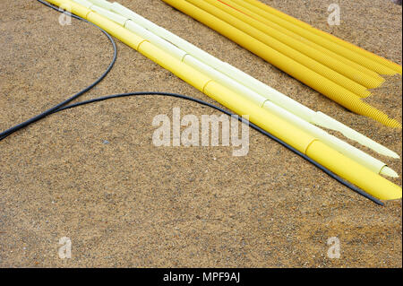 Kabel und Kunststoffrohre in den Sand. Stockfoto