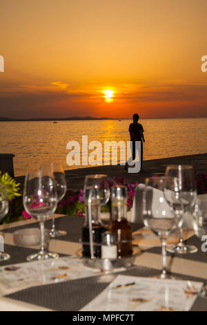 Herrliche goldene Rot und Orange lebendige pulsierende Sonnenuntergang über dem Meer im Hafen von Zadar an der Adriatischen Küste Kroatien von einem Tisch im Restaurant gesehen Stockfoto