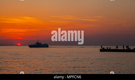 Leute, schöne herrliche goldene Rot und Orange lebendige pulsierende Sonnenuntergang vom Steg über dem Meer an der Adria Hafen von Zadar Kroatien Stockfoto