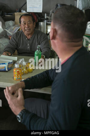 Bokusei Kinjo nimmt sich eine Auszeit von der Arbeit auf seiner Farm in der Nähe von Camp Hansen, Okinawa, Japan, 23. Februar 2017, um mit Gunnery Sgt. Todd Groves zu sprechen. Groves, Fulton, Missouri, wurde ein Schweinezüchter aufgewachsen und jetzt erbietet sich, Land und die Tiere auf Kinjo Bauernhof kümmern. Groves ist eine Wartung Chef mit kleinen Handwerk Reparatur Platoon, Expeditionary Operations Training Group, III. Marine Expeditionary Force. (Foto: U.S. Marine Corps Lance Cpl. Bernadette Wildes) Stockfoto