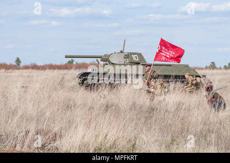 2018-04-30 Die Samara, Russland. Ein Kommandeur mit einem Banner führt in der Schlacht von sowjetischen Soldaten. Wiederaufbau der Kampfhandlungen im April 1945. Stockfoto